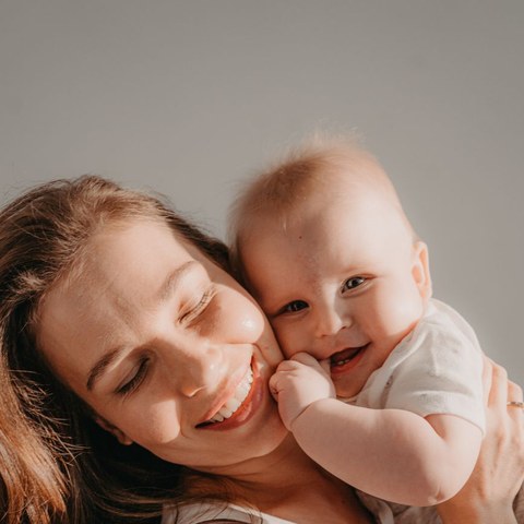 Jenna, a Big Crayon parent, smiling and cuddling her baby