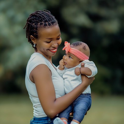 Adaeze, a Big Crayon parent, smiling down at her baby in a pink headband
